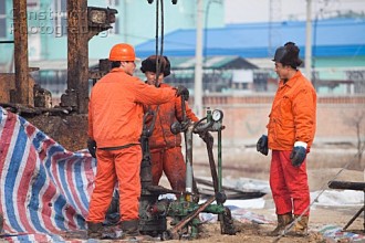 Oil workers drilling a new oil well in the Daqing oil field in Northern China